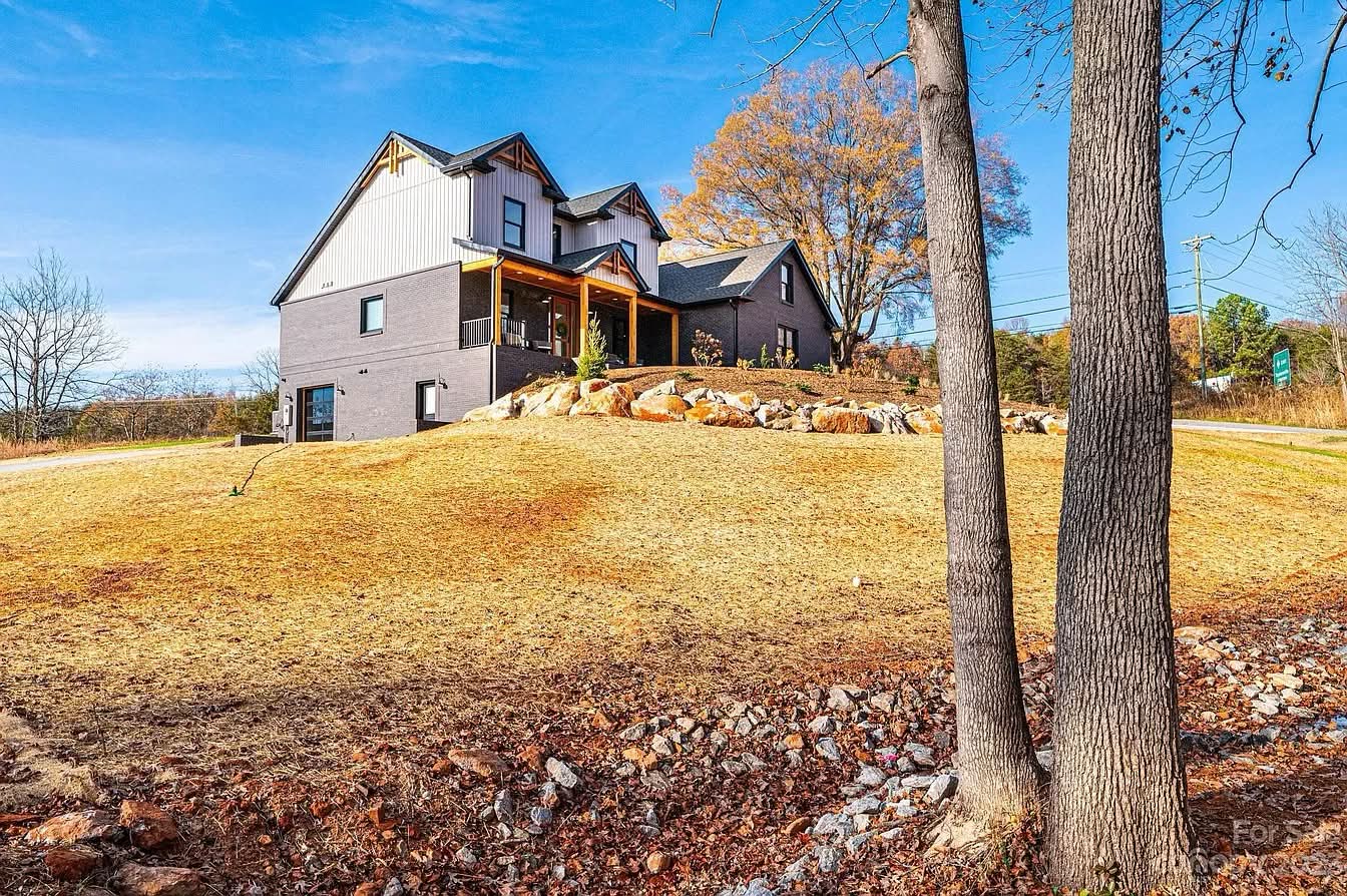 Completed home on a rural hillside lot with trees and graded yard